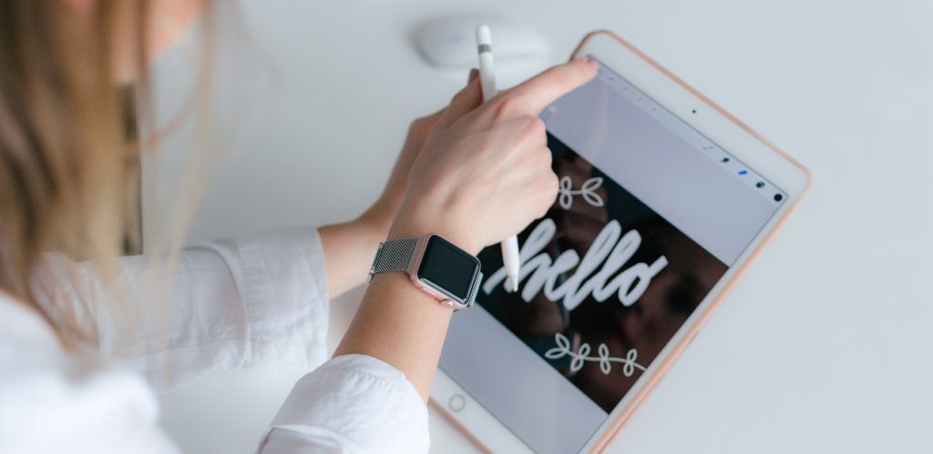 Vemos el perfil de una chica sujetando con sus manos un apple pencil y un ipad donde está realizando un trabajo de lettering